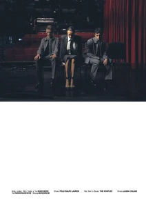 Three models seated in grey tailored suits on a theatre stage with red velvet curtains, photographed by Anastasia and Sasha Laukart for Le Mile Magazine.
