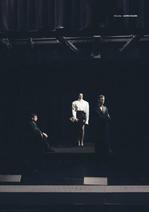 Three models posed on a dark stage with theatrical overhead lighting for an editorial project by Anastasia and Sasha Laukart