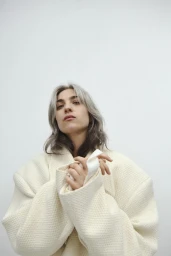 Woman wearing a textured cream jacket with structured shoulders against a plain white background