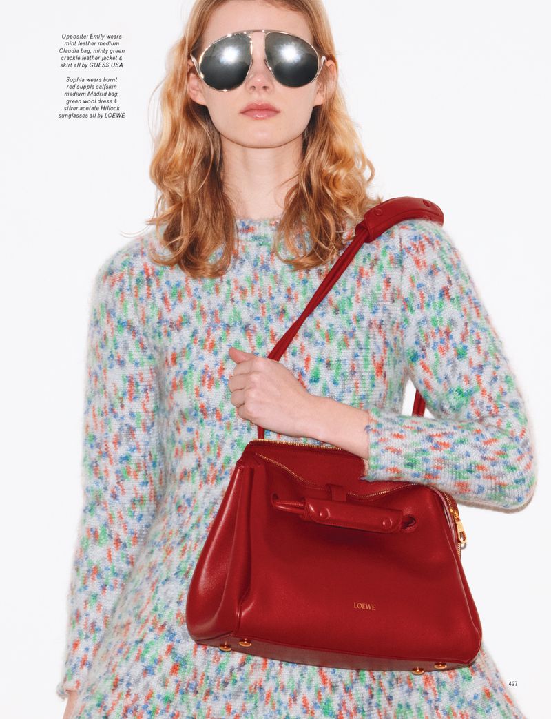 Woman with red handbag in fashion shot wearing aviator sunglasses and patterned dress against white backdrop.
