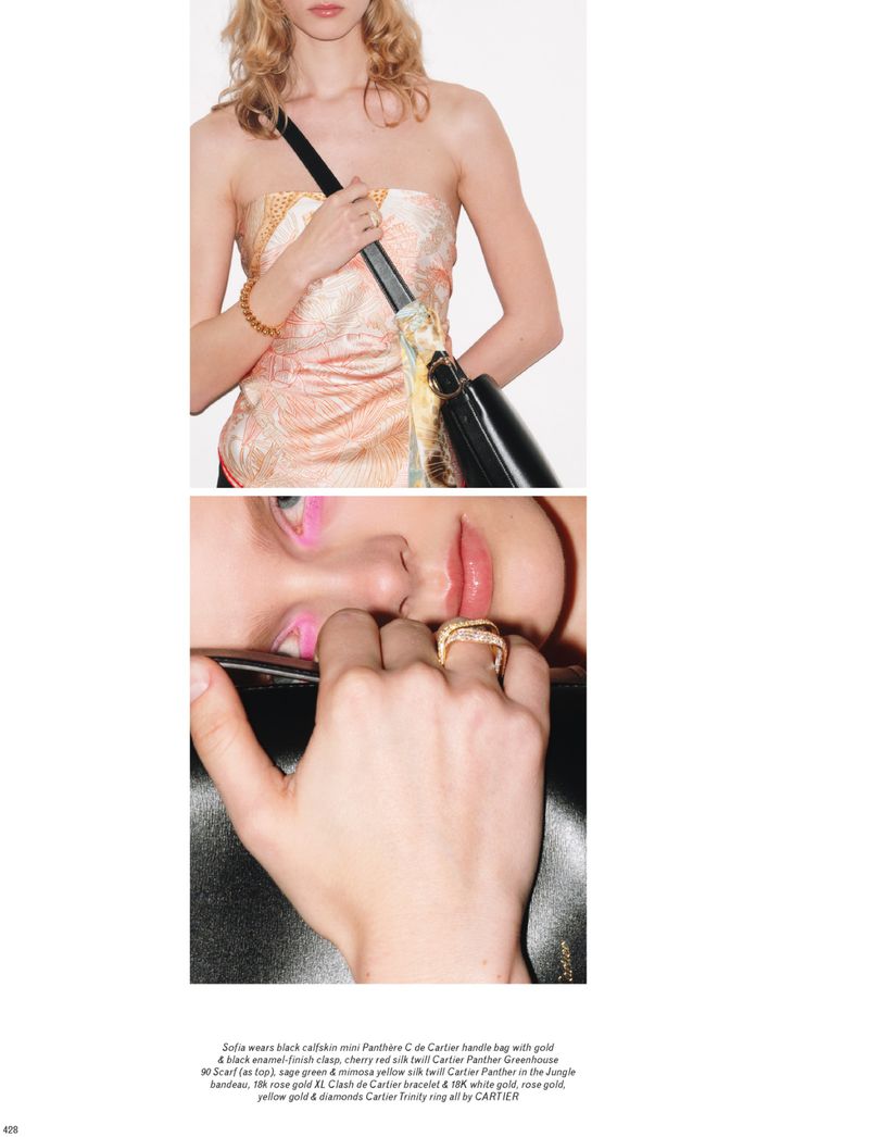 Fashion editorial featuring a blonde model in a strapless top and jewelry, posing indoors with a black handbag, close-up shot.