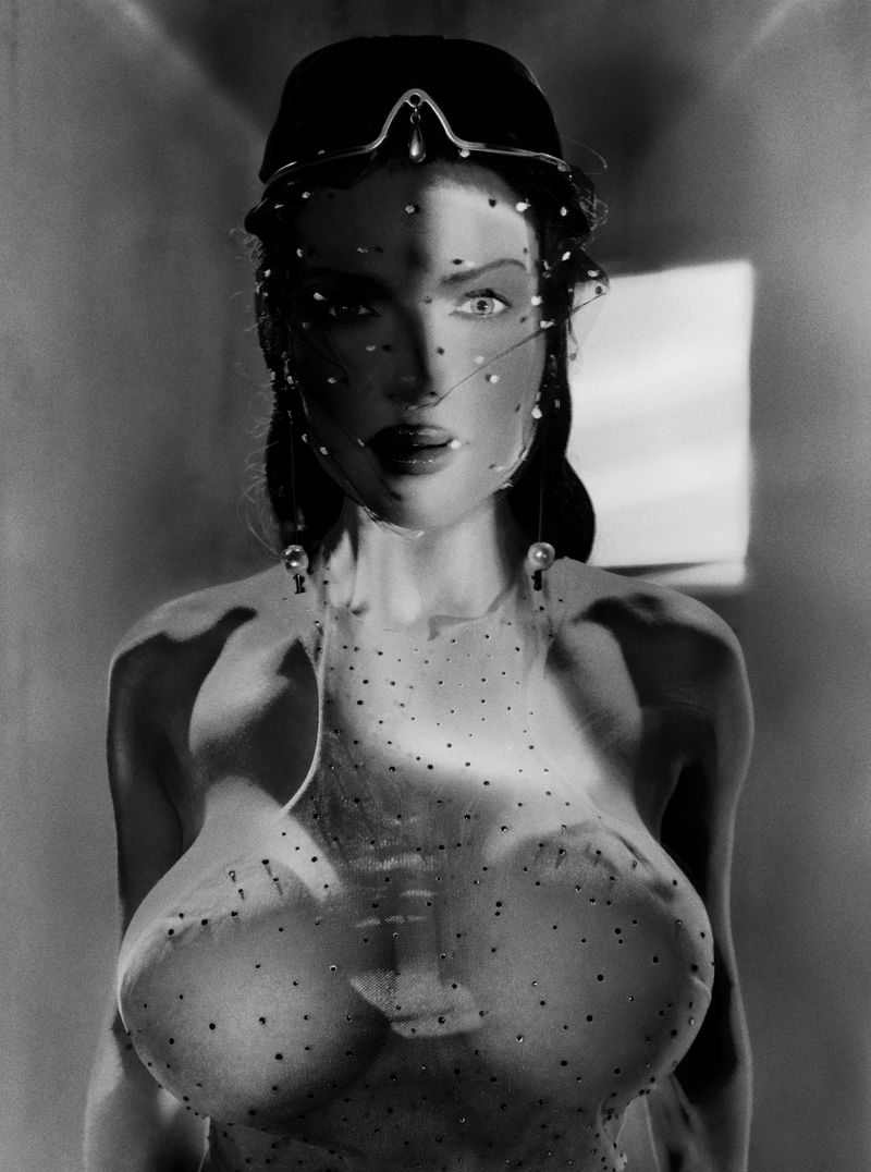 Monochrome portrait of a woman with a veil and decorative headpiece, casting soft shadows in a dimly lit indoor environment.