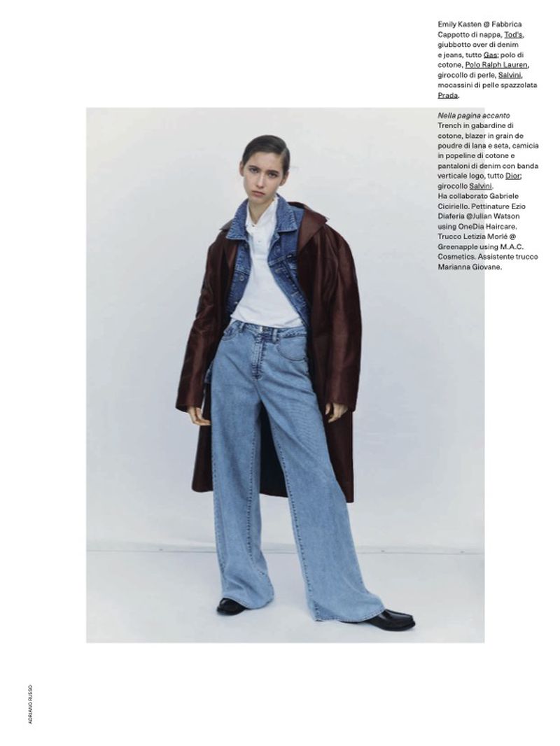 Fashion editorial shot of a woman in a denim jacket and wide-leg jeans with a brown coat, standing against a neutral studio backdrop.
