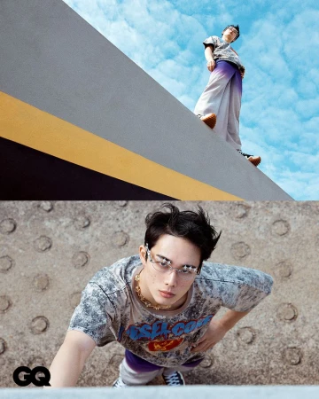 Fashion shot featuring two Asian male models in casual streetwear. One model poses high above against a blue sky, shot from a low angle.