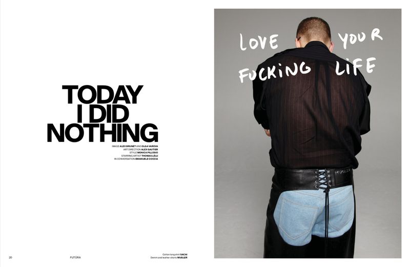 Fashion editorial shot of an adult male wearing a black shirt and denim shorts with chaps in a photo studio against a grey backdrop.