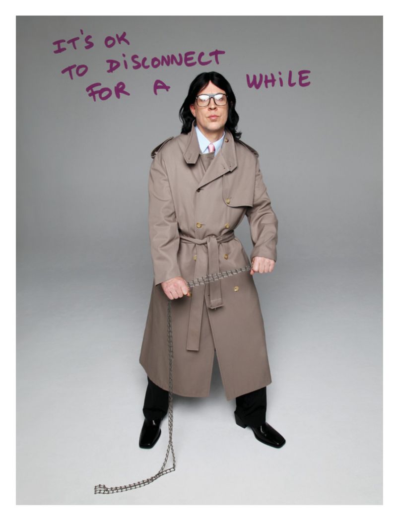 Adult male in a tan trench coat stands indoors, holding a metal chain. Text above reads, “It’s ok to disconnect for a while.