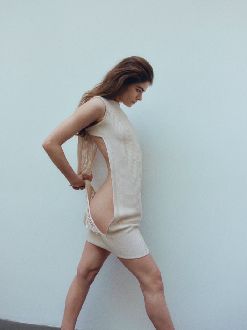 Model in a cream sleeveless side-slit dress against a light grey seamless backdrop for Costume Denmark
