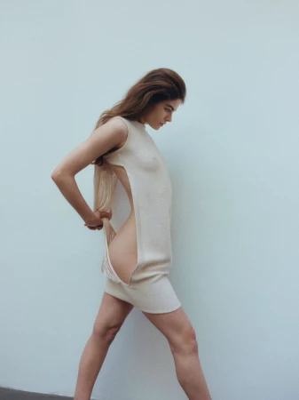 Model in a cream sleeveless side-slit dress against a light grey seamless backdrop for Costume Denmark
