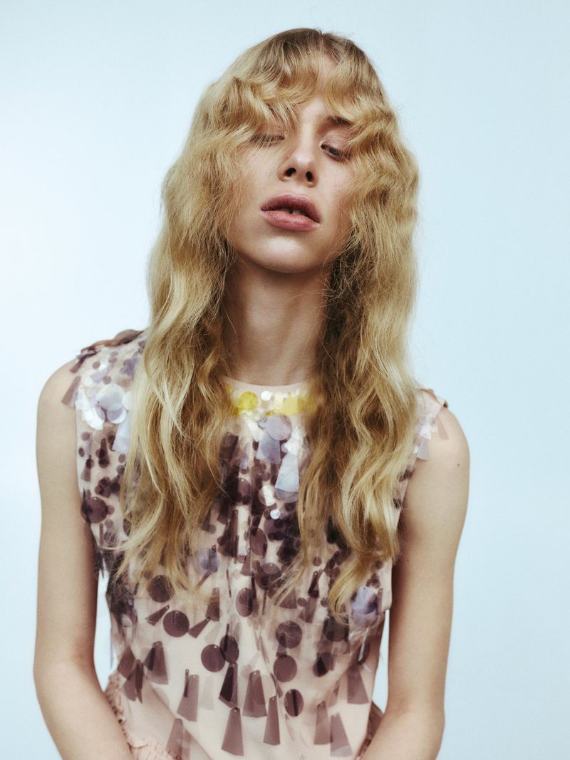 Portrait of a blonde woman wearing a patterned sleeveless top against a pale background for The Collector Magazine Maja editorial project