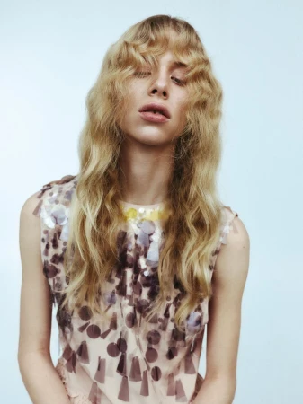 Portrait of a blonde woman wearing a patterned sleeveless top against a pale background for The Collector Magazine Maja editorial project