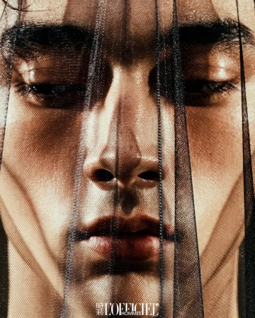 Extreme close-up portrait of a male model's face partially obscured by a sheer black mesh veil, photographed for L'Officiel Hommes China.