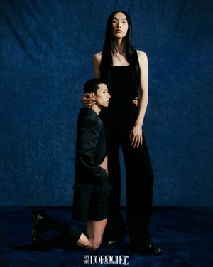 Two male models posing against a dark blue textured backdrop for an editorial feature in L'Officiel Hommes China.