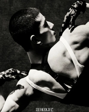 Monochrome portrait of a man wearing lace gloves and harness straps against a textured dark background for L'Officiel Hommes China.