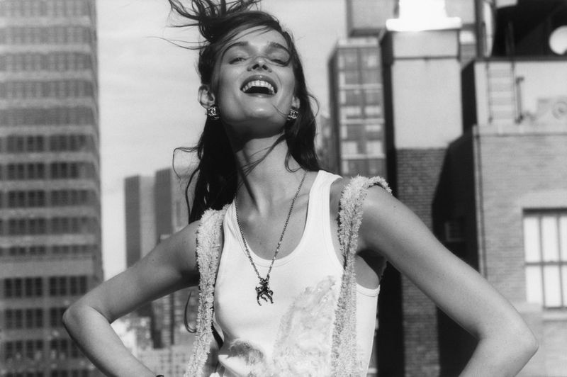 Model Lulu Tenney laughing outdoors on a rooftop wearing a white tank top for Pop Magazine