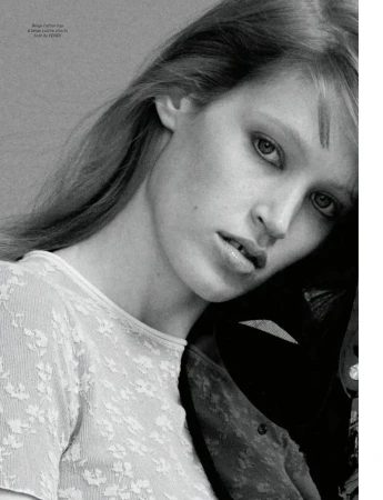 Close-up portrait of model Jacqui Hooper wearing a white patterned top against a plain textured grey background.