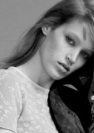 Close-up black and white portrait of model Jacqui Hooper in a textured patterned top against a plain studio backdrop.