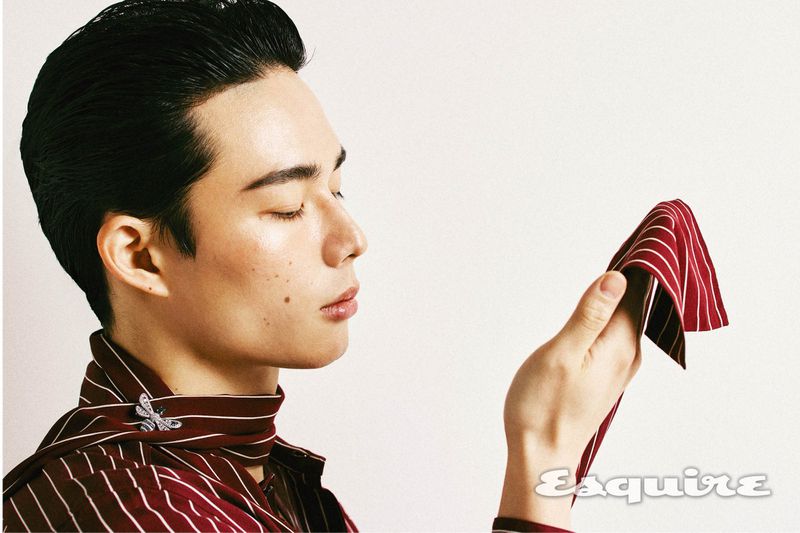 Asian man in profile with a red striped neck scarf and handkerchief. He's posed in a photo studio with a white backdrop.