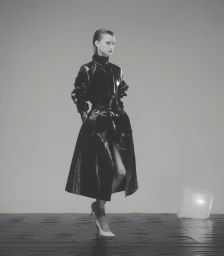 Model Dana Smith wearing a black glossy belted coat and heels in D Repubblica High Voltage editorial by Casper Sejersen.