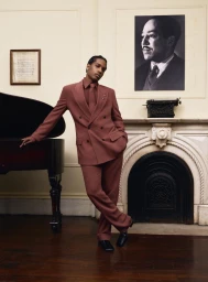 A$AP Rocky leaning against a grand piano wearing a matching brown suit for American Vogue photographed by Tyler Mitchell.