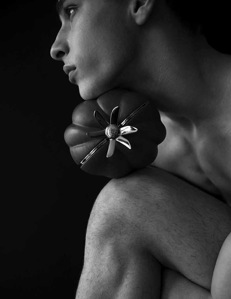 Black and white studio shot of a bare-chested adult male with a shoulder-length decorative jar against a dark background.