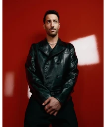 Daniel Ricciardo wearing a dark leather jacket against a bold red studio backdrop for GQ Australia.