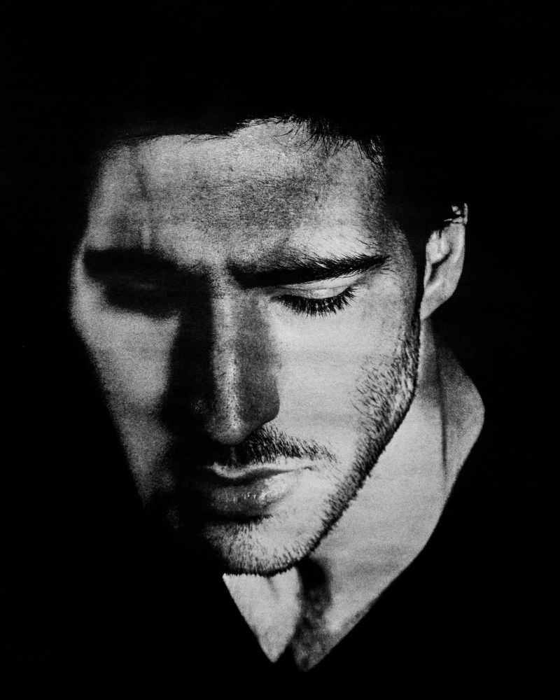 Monochrome portrait of a male face with a beard, captured in a low-key lighting setup, highlighting facial contours and dramatic shadows.