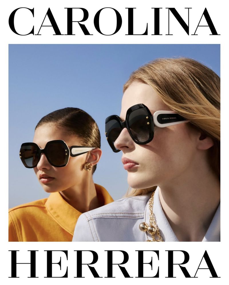 Two models showcase Carolina Herrera sunglasses against a clear blue sky. One wears a yellow jacket, the other a denim jacket.