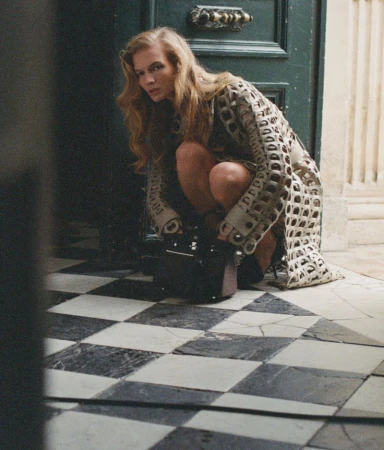 Model Caitlin Soetendal crouching in a patterned cutout coat on a checkered marble floor for D Repubblica Pause editorial
