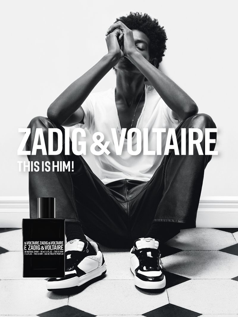 Black and white fashion-style image featuring a man in a seated pose, apparel, shoes, and a bottle of Zadig & Voltaire cologne.