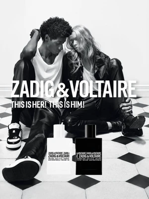 Black and white advertising campaign image for Zadig & Voltaire featuring two models seated on a checkered floor with two fragrance bottles.
