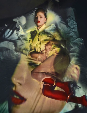 Overhead studio shot of a fashion model lying on a bed, red high heel boots on, and a face double exposure. Fashion and beauty editorial.