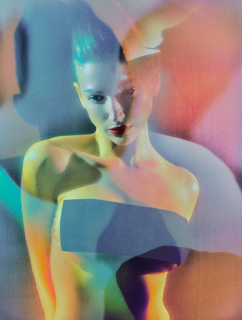 Woman with cyan hair and red lipstick in a studio portrait featuring vibrant neon lighting, creating a modern and artistic aesthetic.