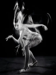 Úrsula Corberó in motion captured with long exposure light trails wearing a sparkling fringe dress against a black background