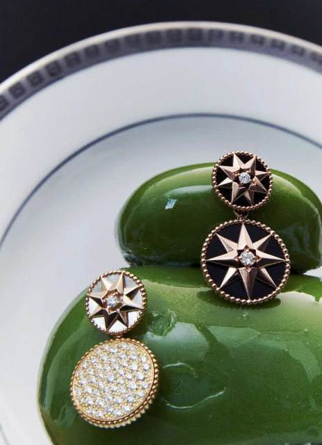 Elegant earrings with star designs displayed on a green surface with a plate in the background, showcasing jewelry and design.