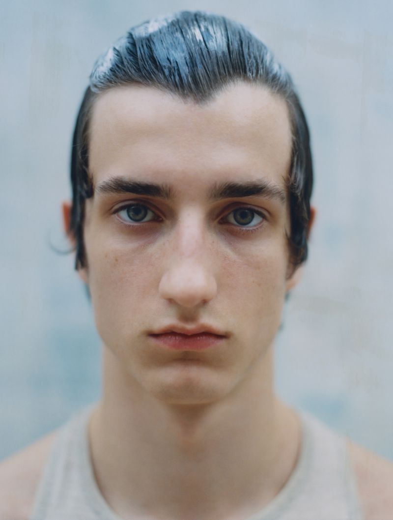 Close-up portrait of model Connor Newall with slicked wet hair and neutral expression against a plain background