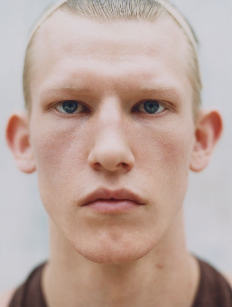 Close-up studio shot of an adult male with light complexion and blue eyes looking directly at the camera with a neutral expression.
