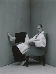 Model Connor Newall seated in an armchair in a grey corner studio set for Lampoon Magazine