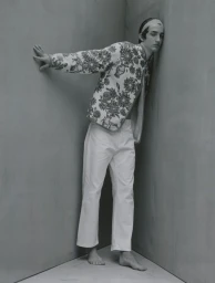 Model leaning against a corner in a floral patterned jacket and white pants for Lampoon Magazine project Between us three.