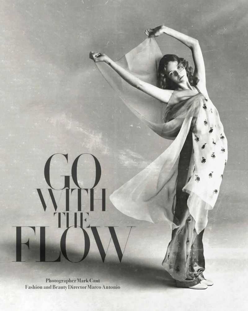 Fashion editorial shot of a woman draped in sheer fabric, gracefully posing against a neutral backdrop with flowing fabric and elegant style.