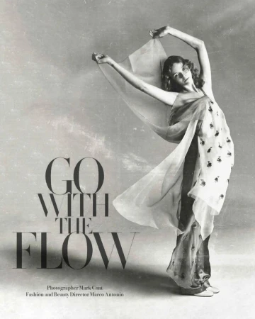 Fashion editorial shot of a woman draped in sheer fabric, gracefully posing against a neutral backdrop with flowing fabric and elegant style.