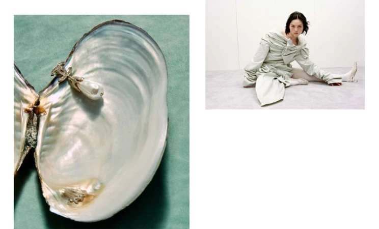 Fashion shot featuring a woman in an draped garment seated on the floor and a large open oyster shell on a green background.