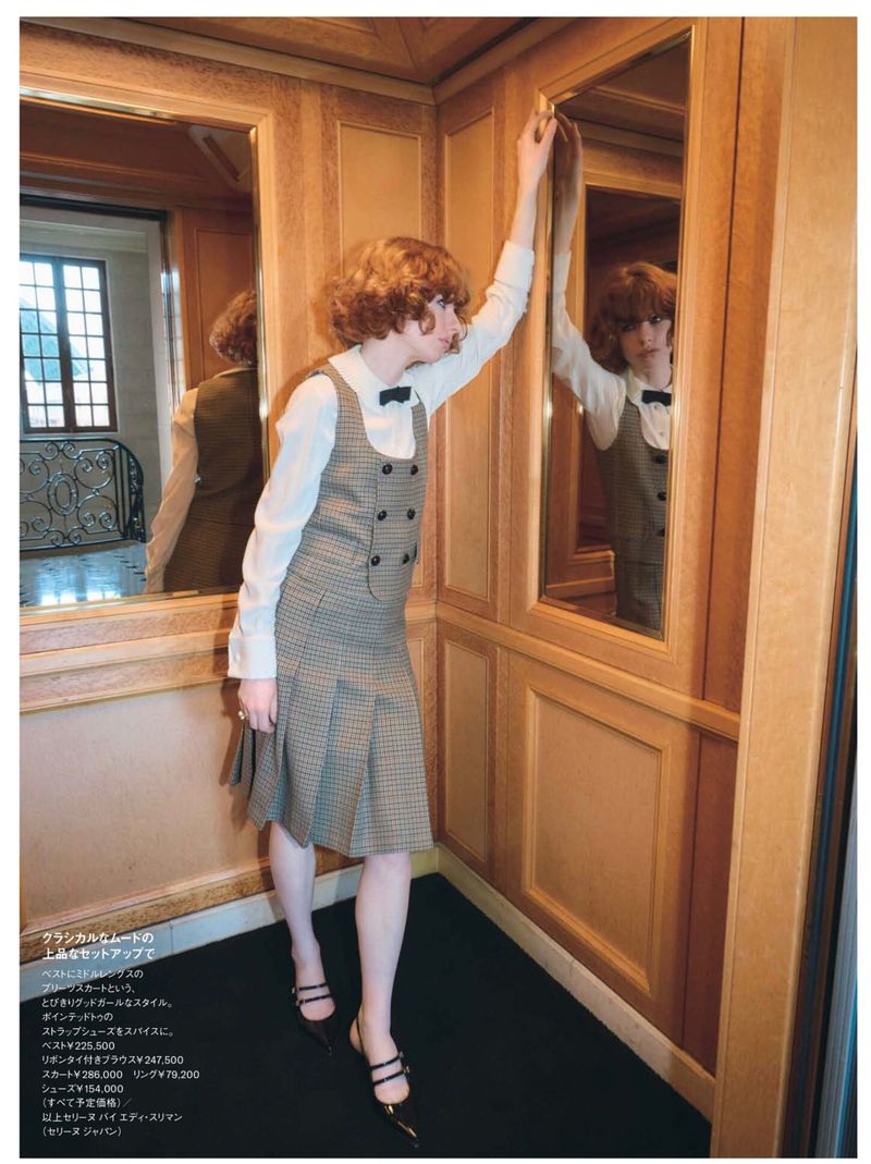 Woman in a retro dress with vest and bow tie, leaning against the mirrored elevator wall, vintage fashion with a modern twist.