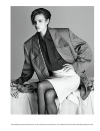 Model wearing an oversized grey blazer and light skirt seated in a studio setting for Pop Magazine editorial.