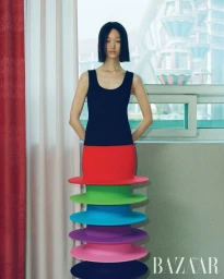 Model Chloe Oh wearing a structured colorful layered skirt standing indoors for Harper's Bazaar Korea