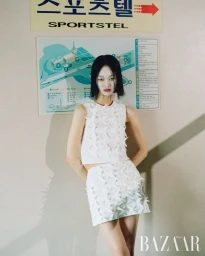 Model Chloe Oh in a white textured top and skirt standing in front of a beige wall with a building diagram sign for Harper's Bazaar Korea.