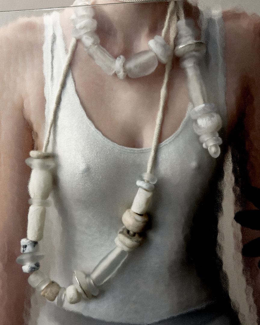 Close-up of a person wearing a white tank top and a chunky beaded necklace, showcasing a unique, handcrafted jewelry piece.