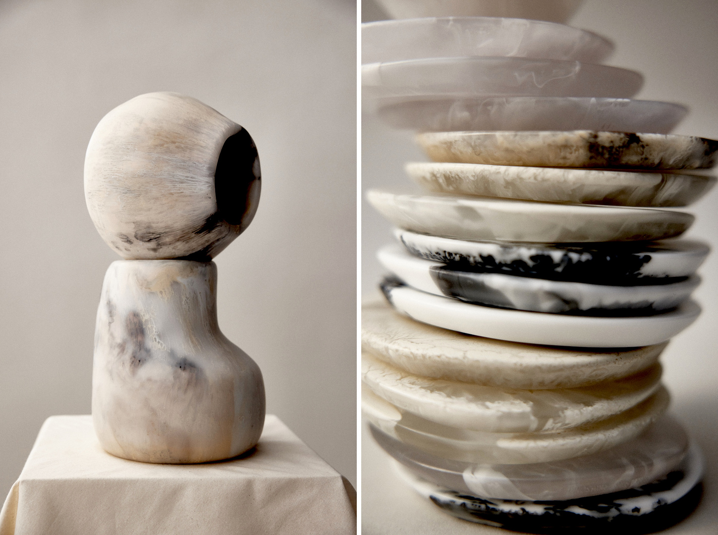 Monochrome art still life featuring sculptural forms in white, cream, and black marble-like textures, contrasted with a stack of round plates.