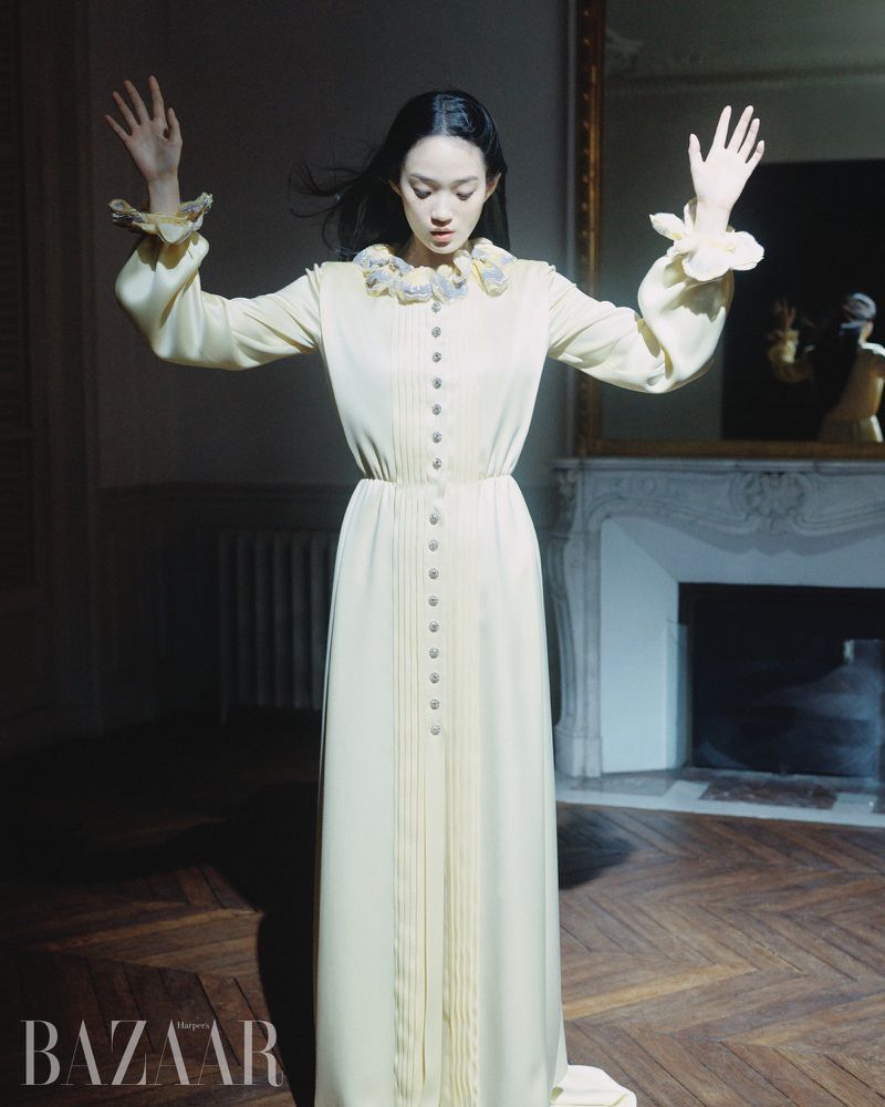 Model Hyunji Shin in a long light yellow dress with ruffled collar standing in a classic room for Harper's Bazaar Korea