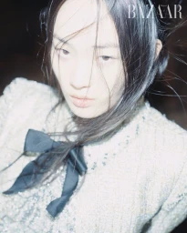 Close-up portrait of model Hyunji Shin wearing a tweed jacket with a black bow for Harper's Bazaar Korea.