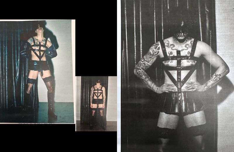 Fashion shot of a tattooed man in a latex harness and briefs, standing in front of a shiny black curtain, bold editorial style.
